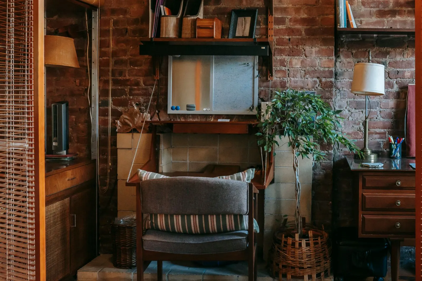 Comfortable chair and shelves attached to brick wall in cozy work zone in vintage styled apartment